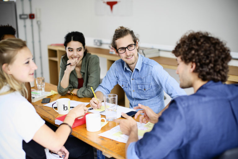 A group of young adults engaged in a lively discussion at a casual meeting.