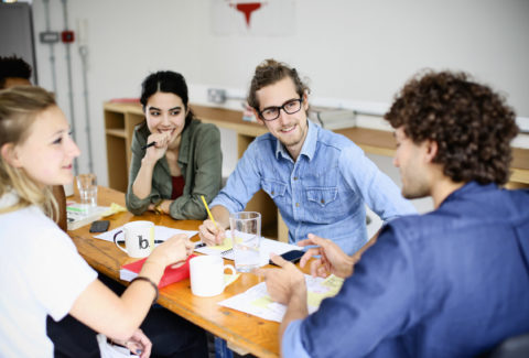 A group of young adults engaged in a lively discussion at a casual meeting.